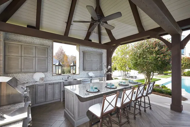Outdoor kitchen cabinetry under a timber pavilion by the pool