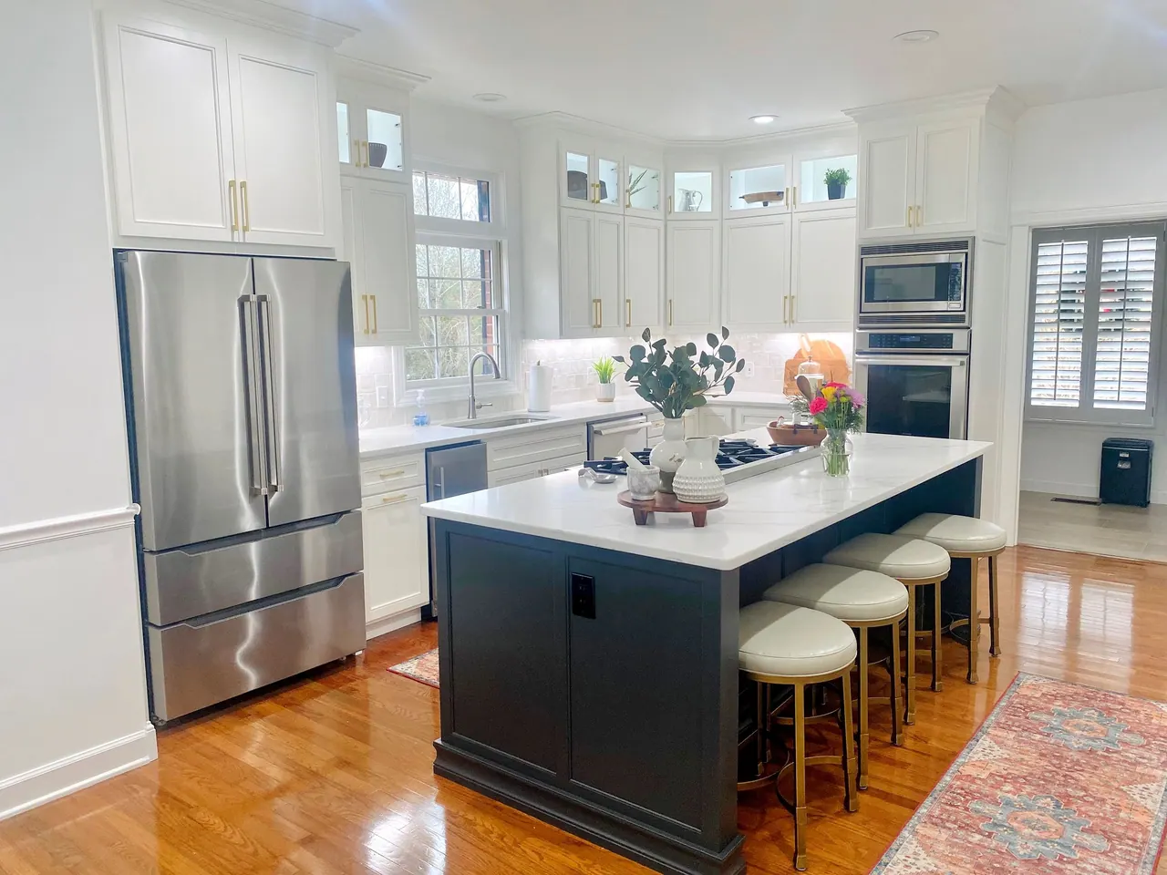 White kitchen with navy island, glass-front uppers and stainless appliances