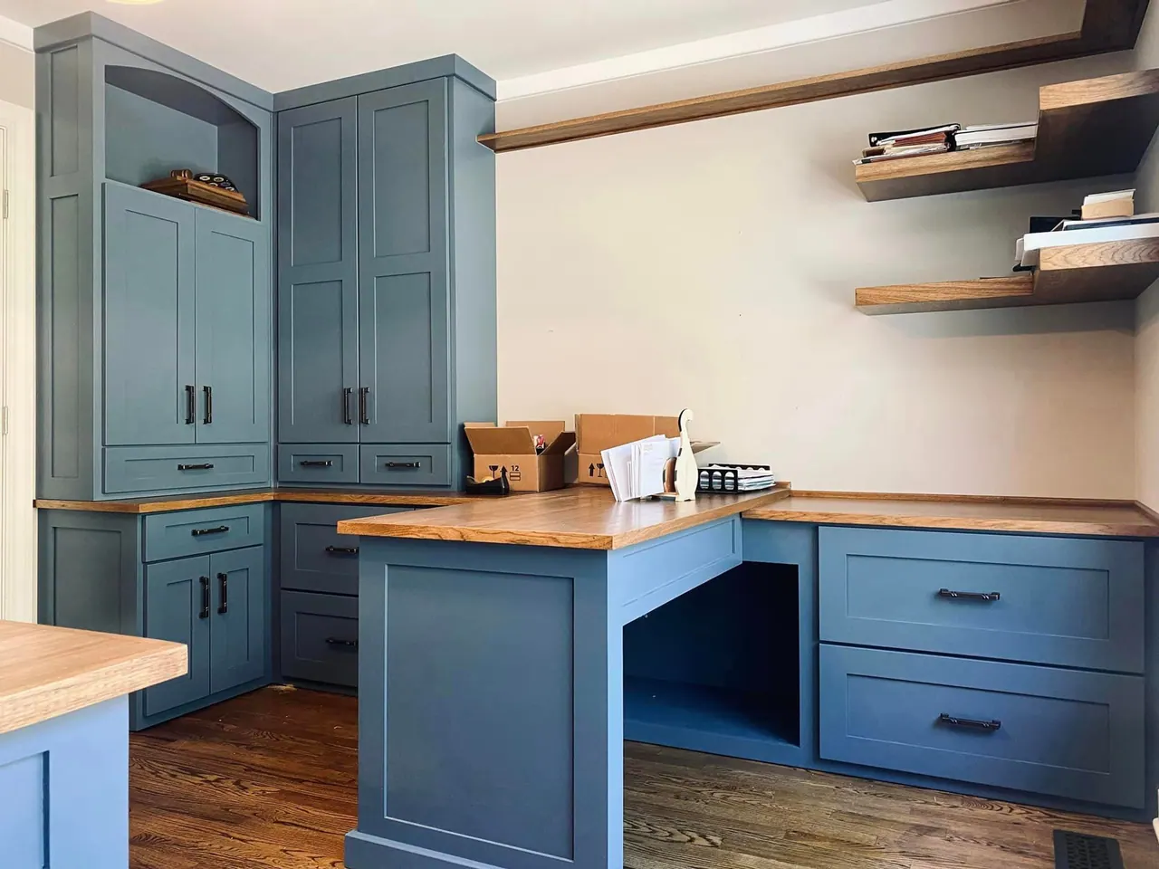 Blue built-in desks with tall cabinets and floating shelves