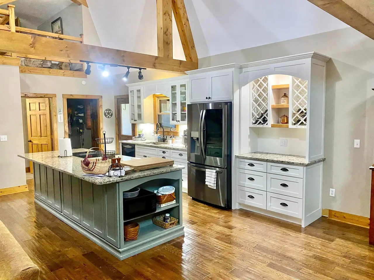 Vaulted kitchen with sage island and white hutch with wine lattice