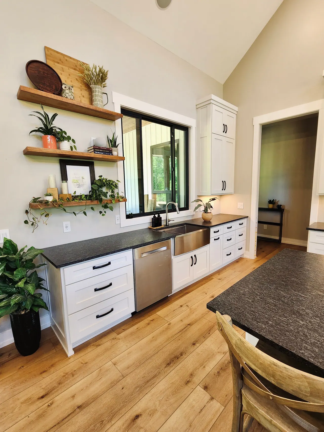 Open wood shelves beside a window over the sink