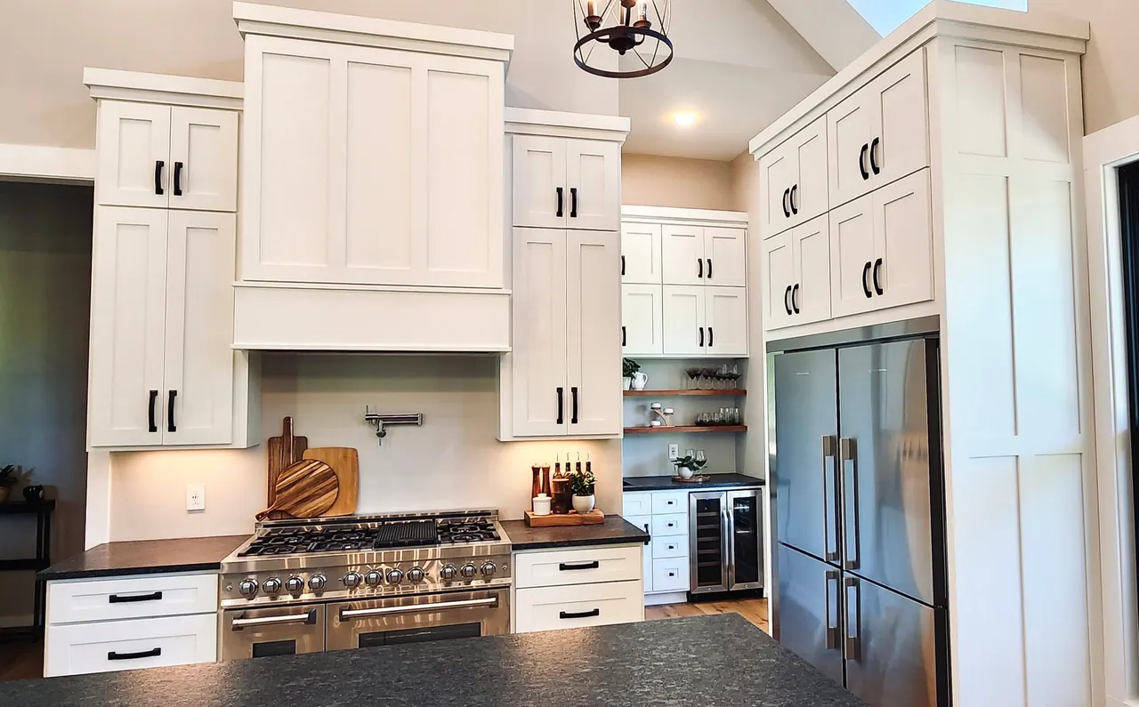 Wide view of tall white cabinetry and range hood