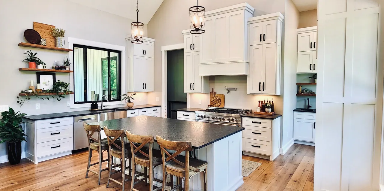 Vaulted white kitchen with dark island and open shelving by the windows