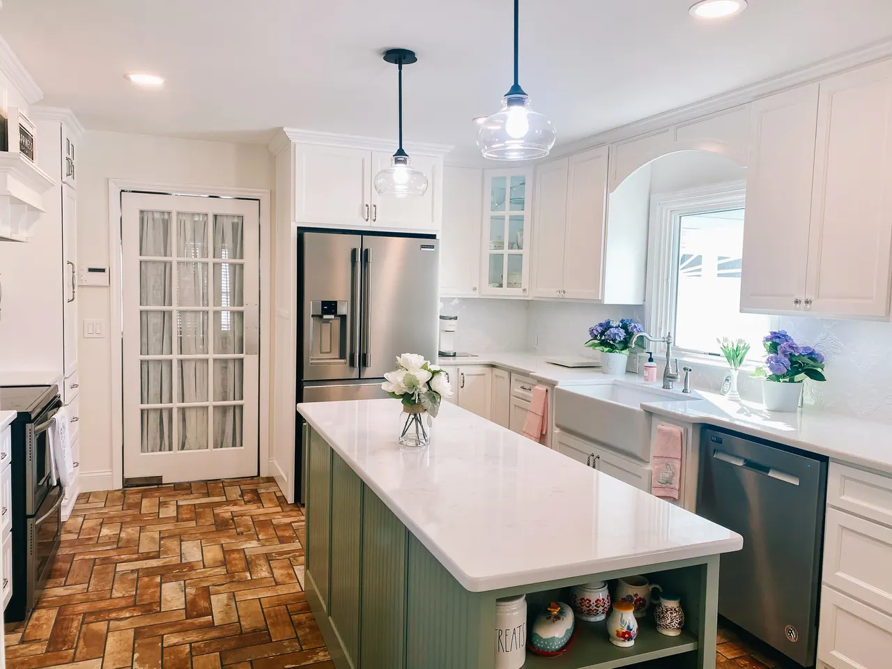 White kitchen with green island and glass pendants