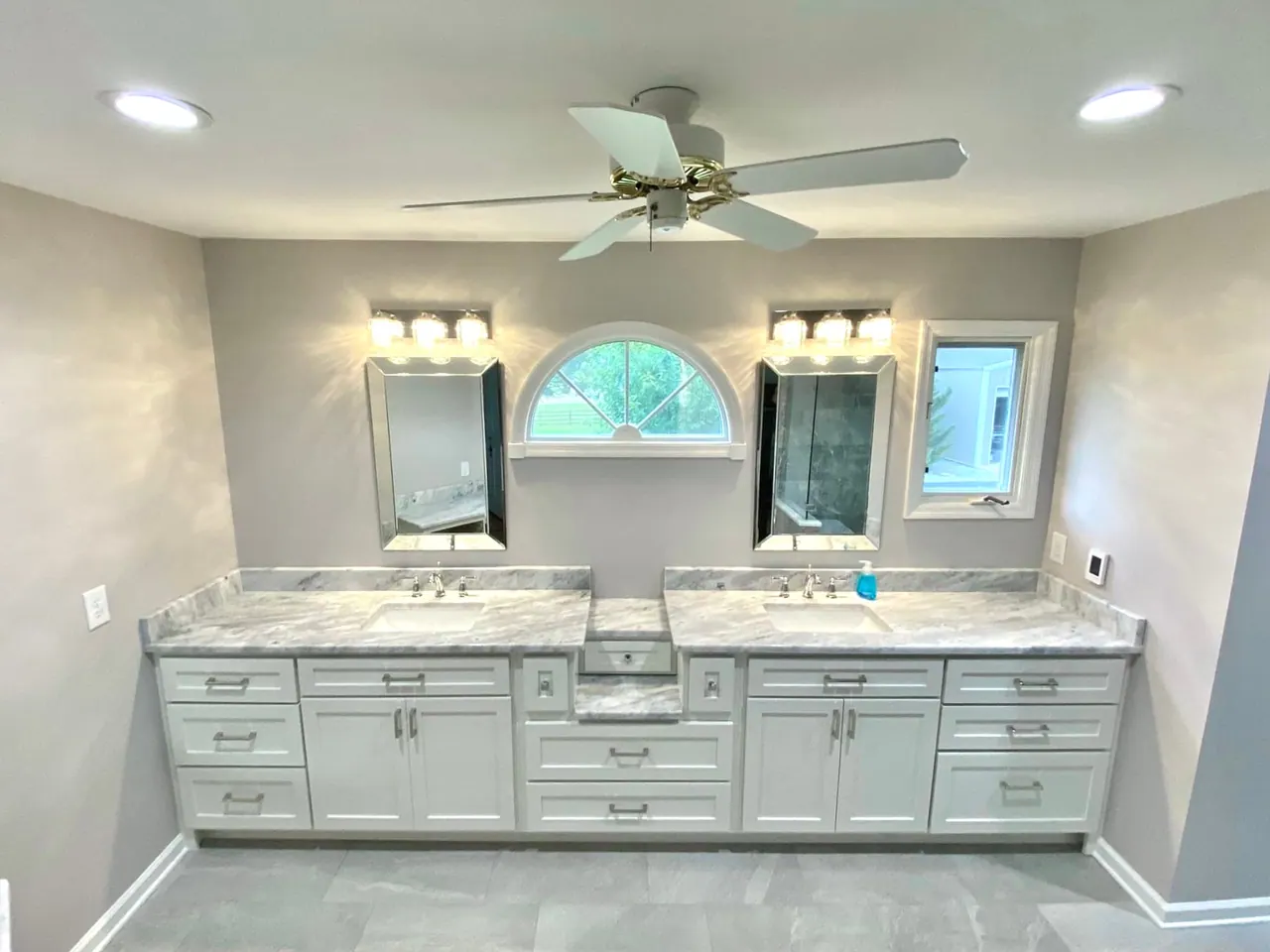 Long white double vanity under arched window