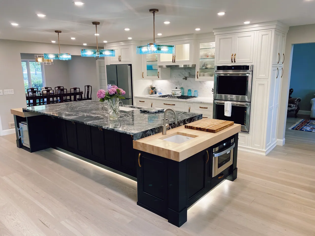 White kitchen with black island, double ovens and pendant lights