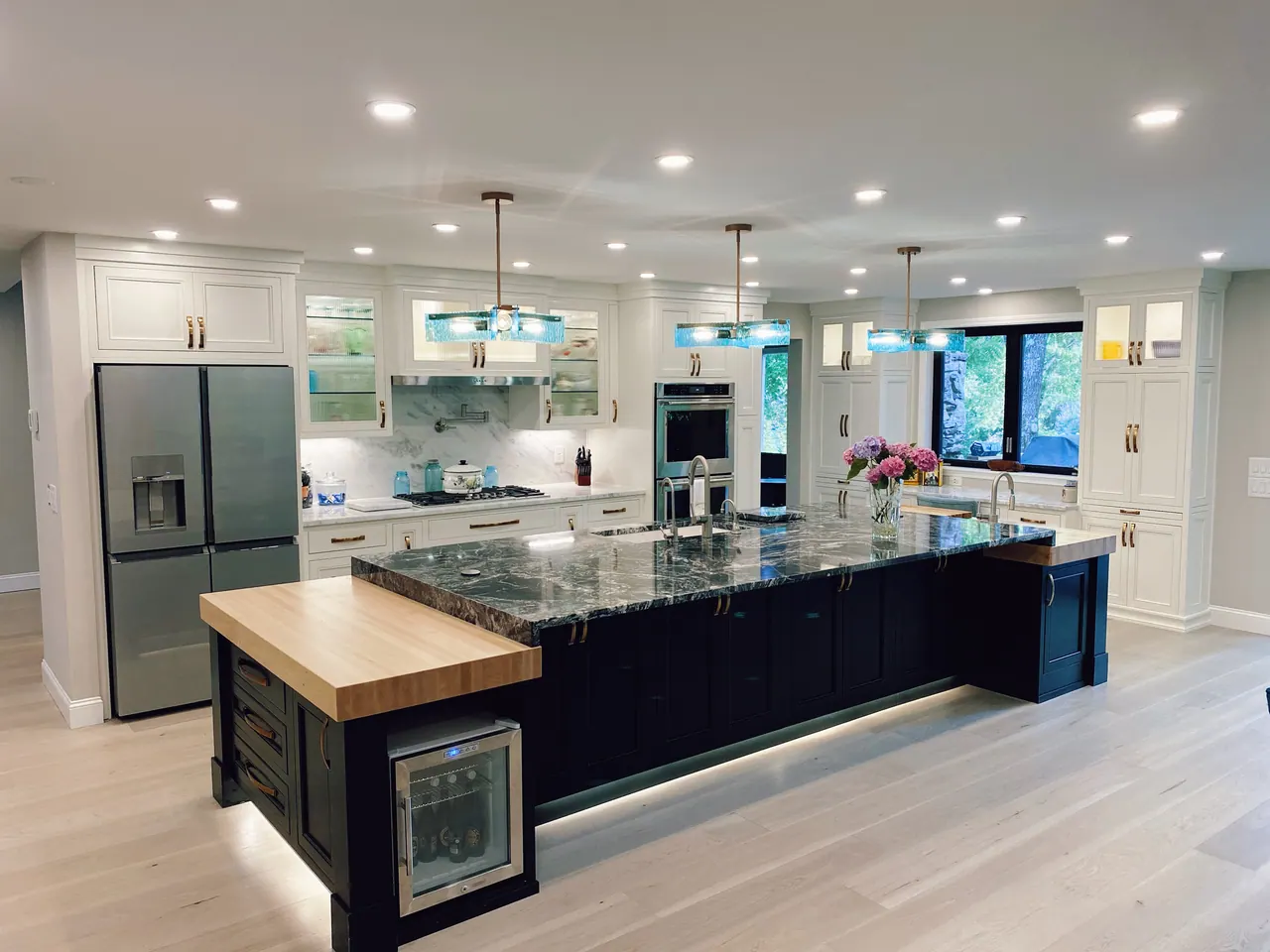 Large black kitchen island with butcher block top and toe-kick lighting