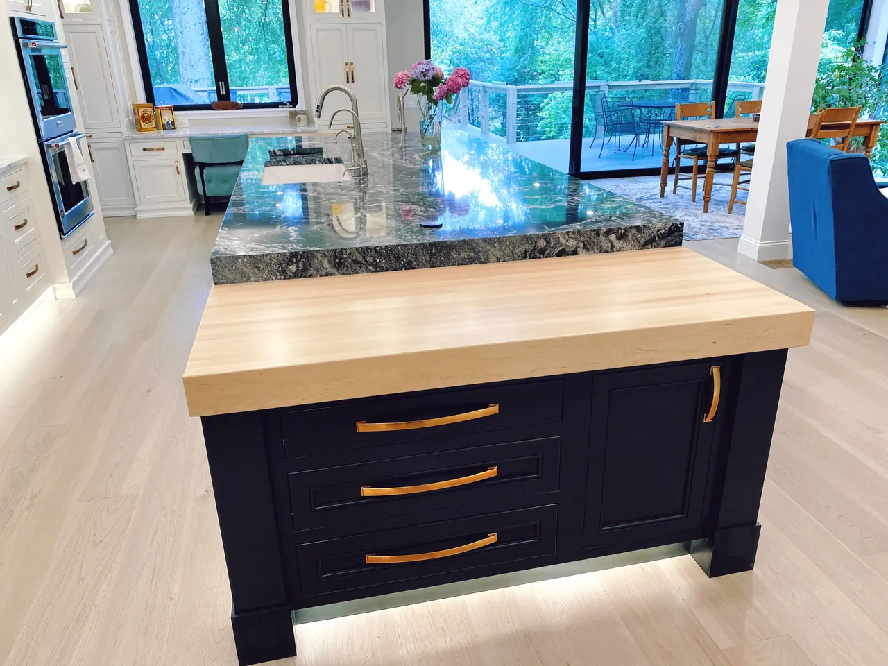 Butcher block prep area on a black island facing a window wall