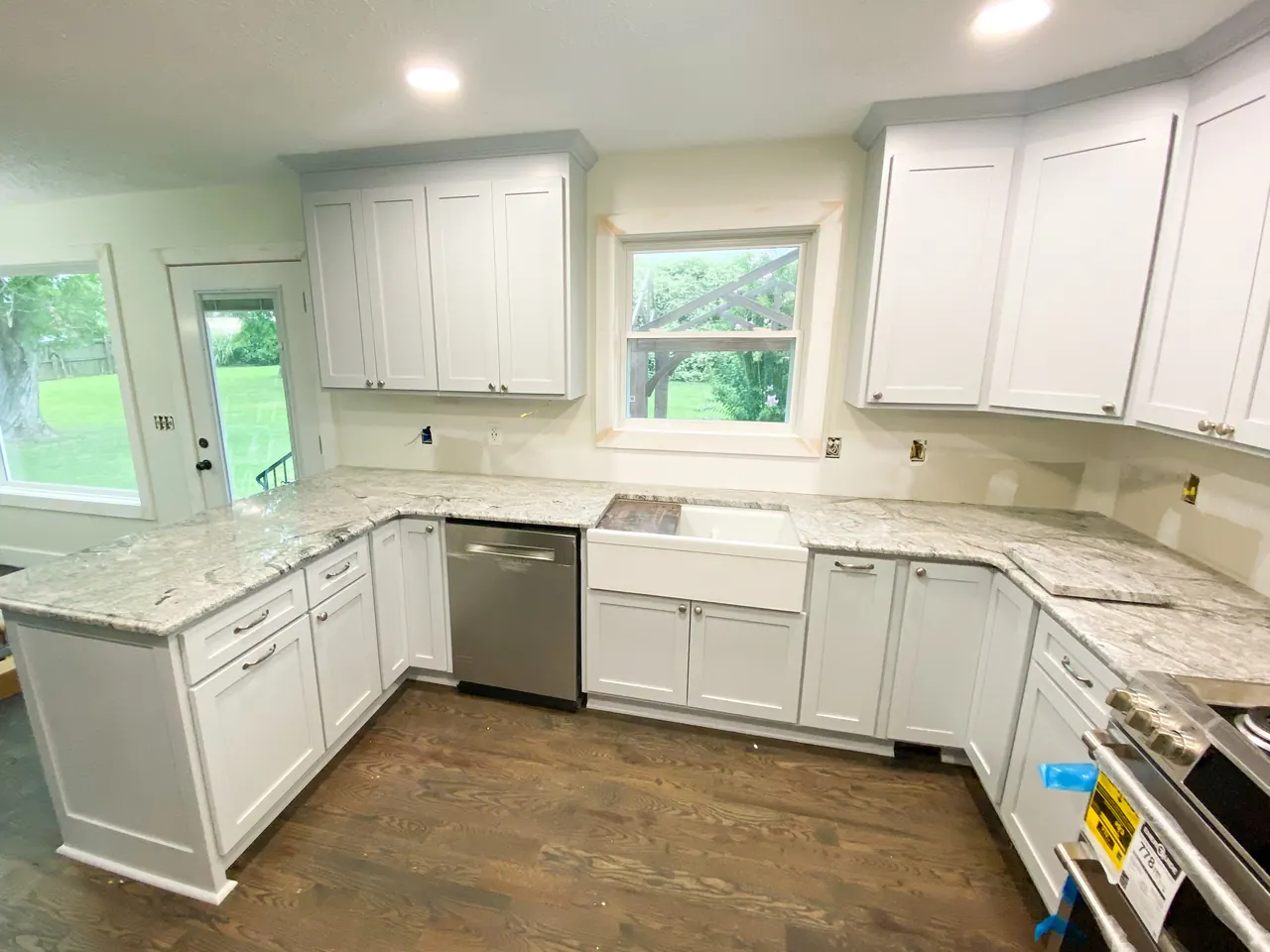 White L-shaped kitchen with apron sink and granite