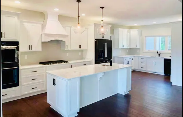 White kitchen with chimney hood and large island