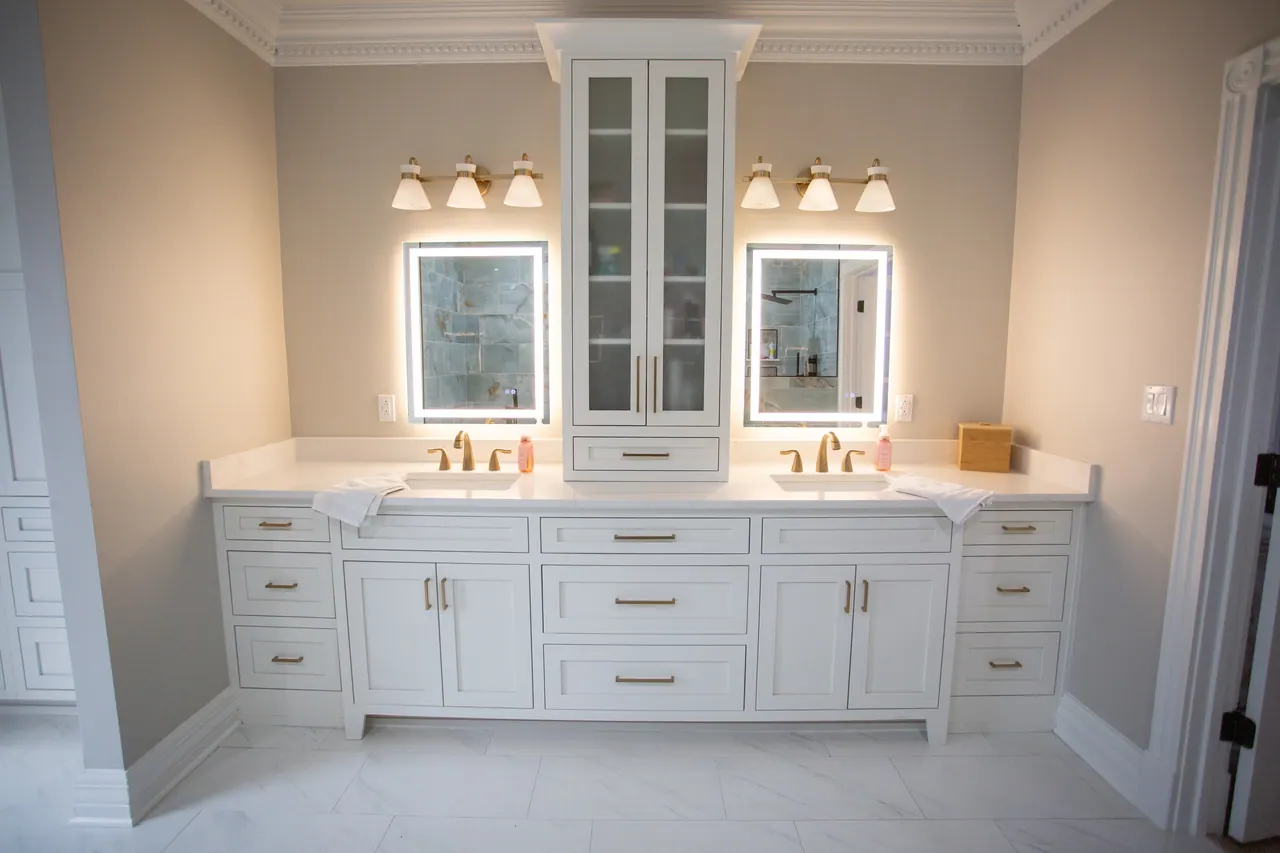 White double vanity with glass center tower and lit mirrors