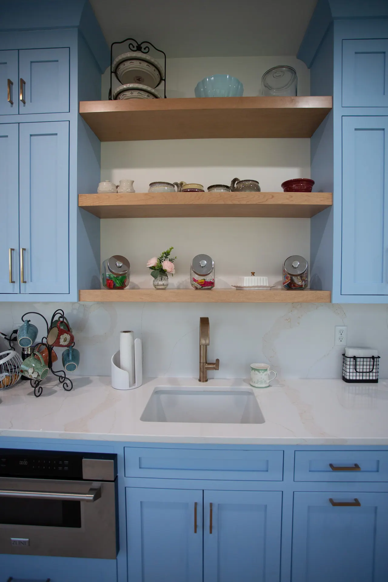 Floating walnut shelves over blue base cabinets