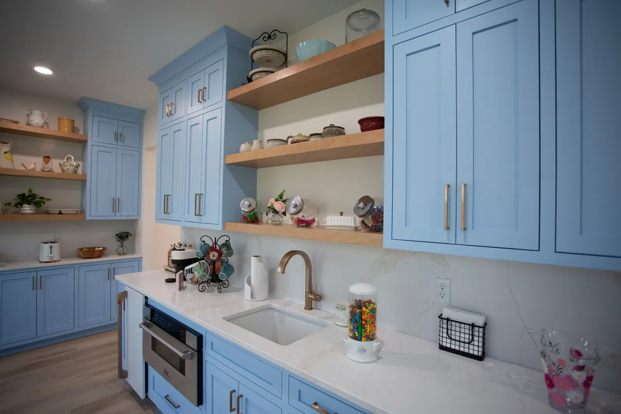 Blue cabinetry with floating wood shelves beside a window sink