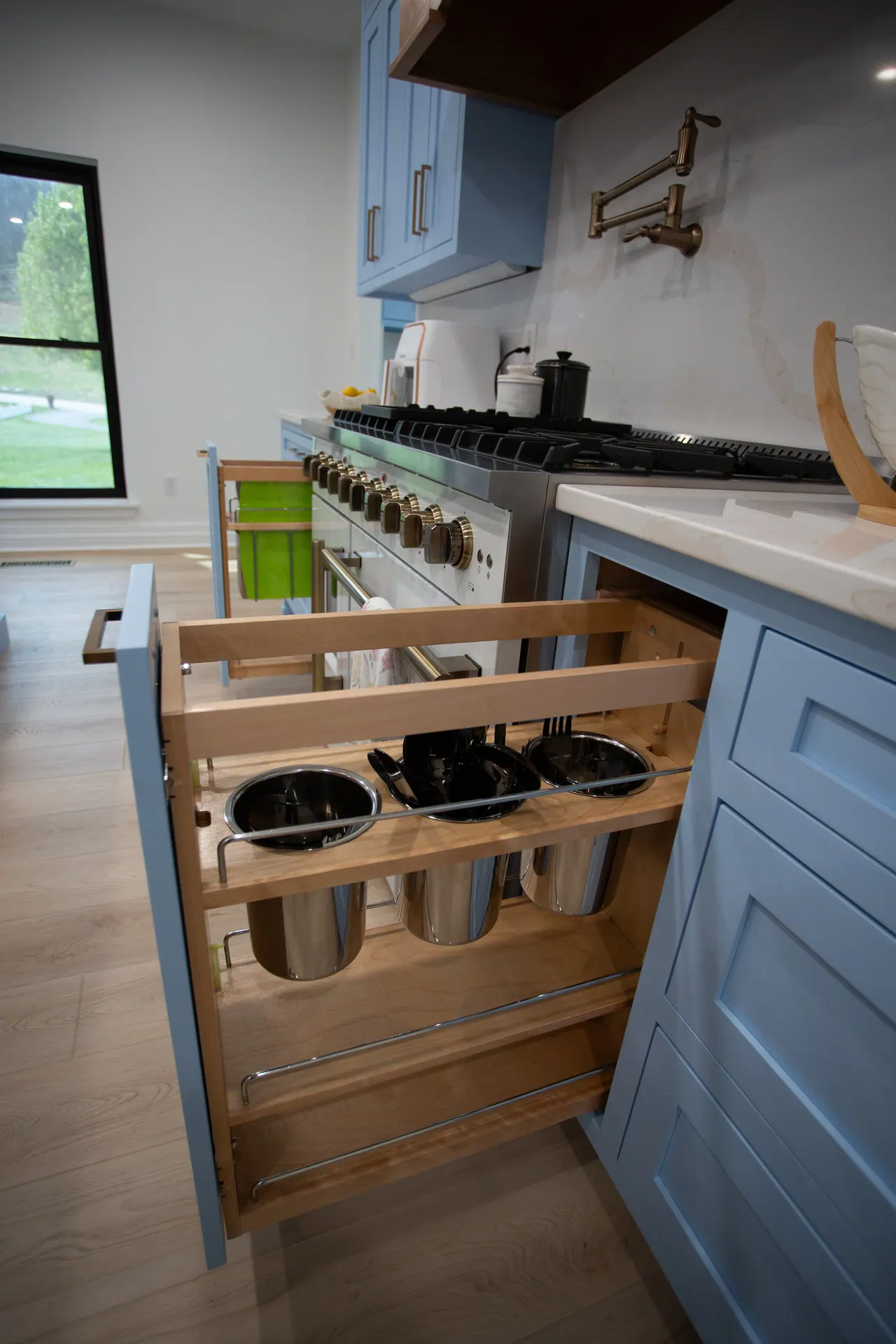 Pull-out spice and utensil organizer beside the range in a blue kitchen
