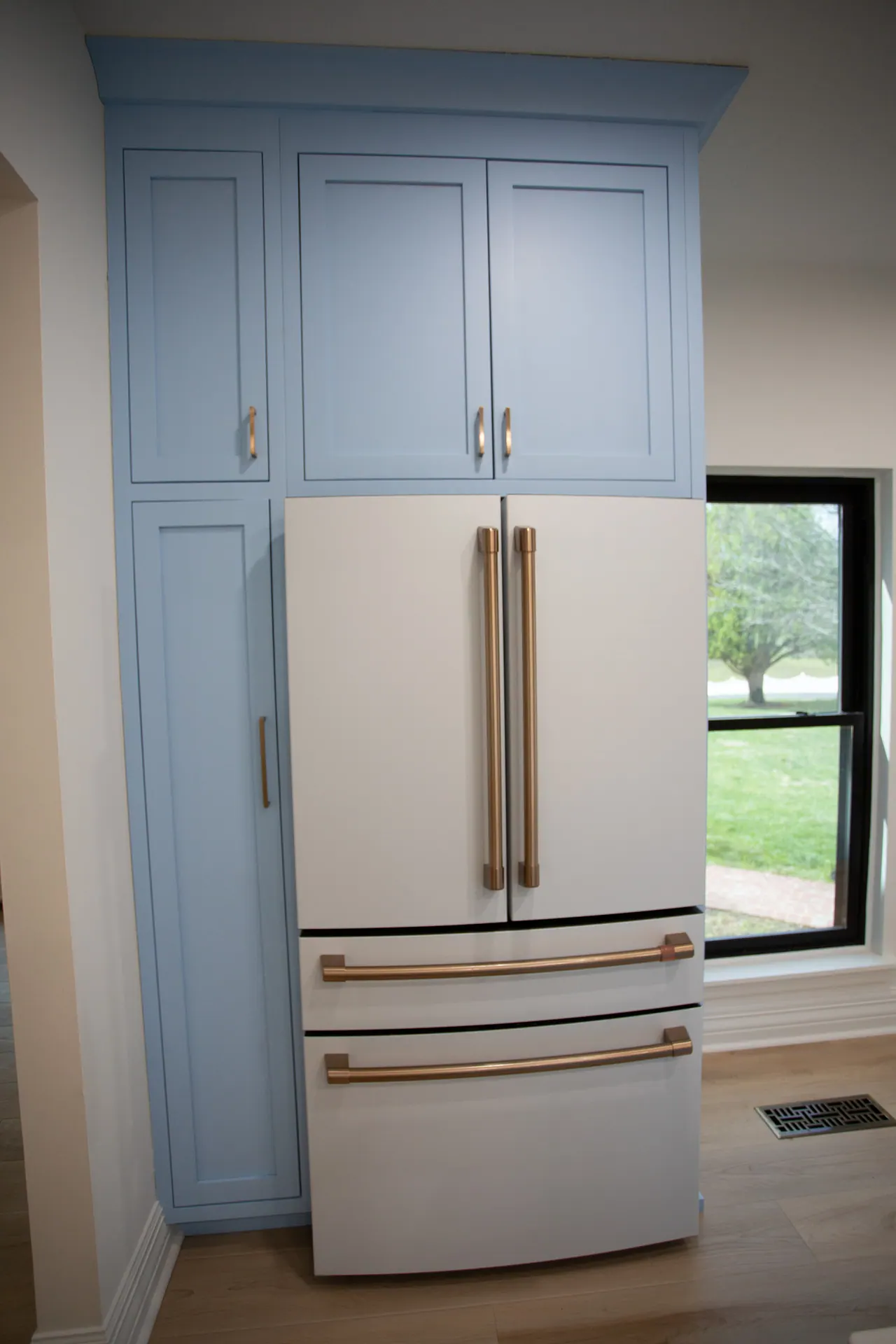 Tall blue pantry cabinets surrounding a white refrigerator