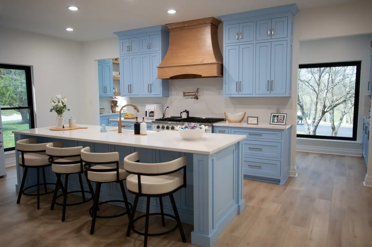 Island seating and wood range hood in a finished blue kitchen