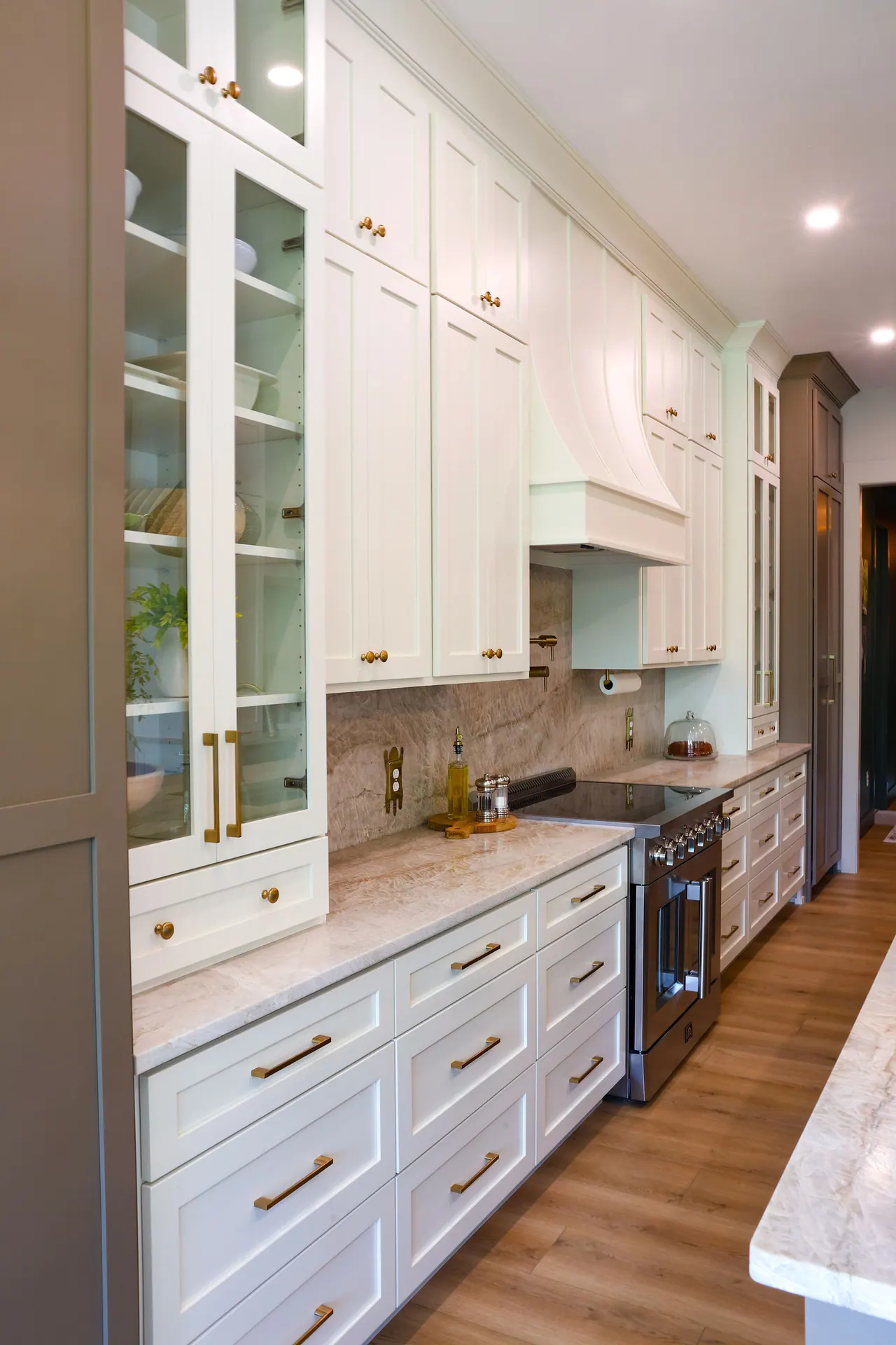 White perimeter cabinets with glass doors and a stained tall cabinet