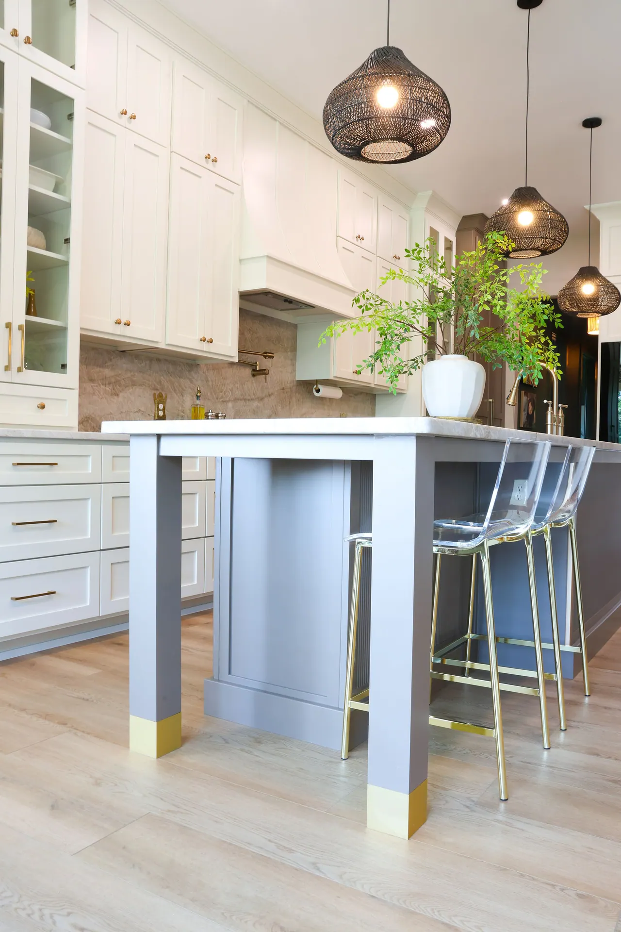White kitchen island with seating beneath woven pendants
