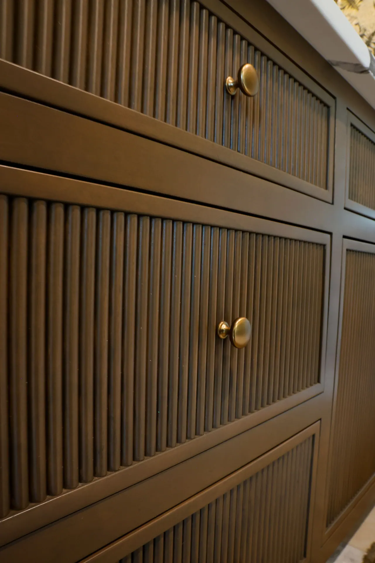 Close-up of fluted cabinet doors with brass knobs