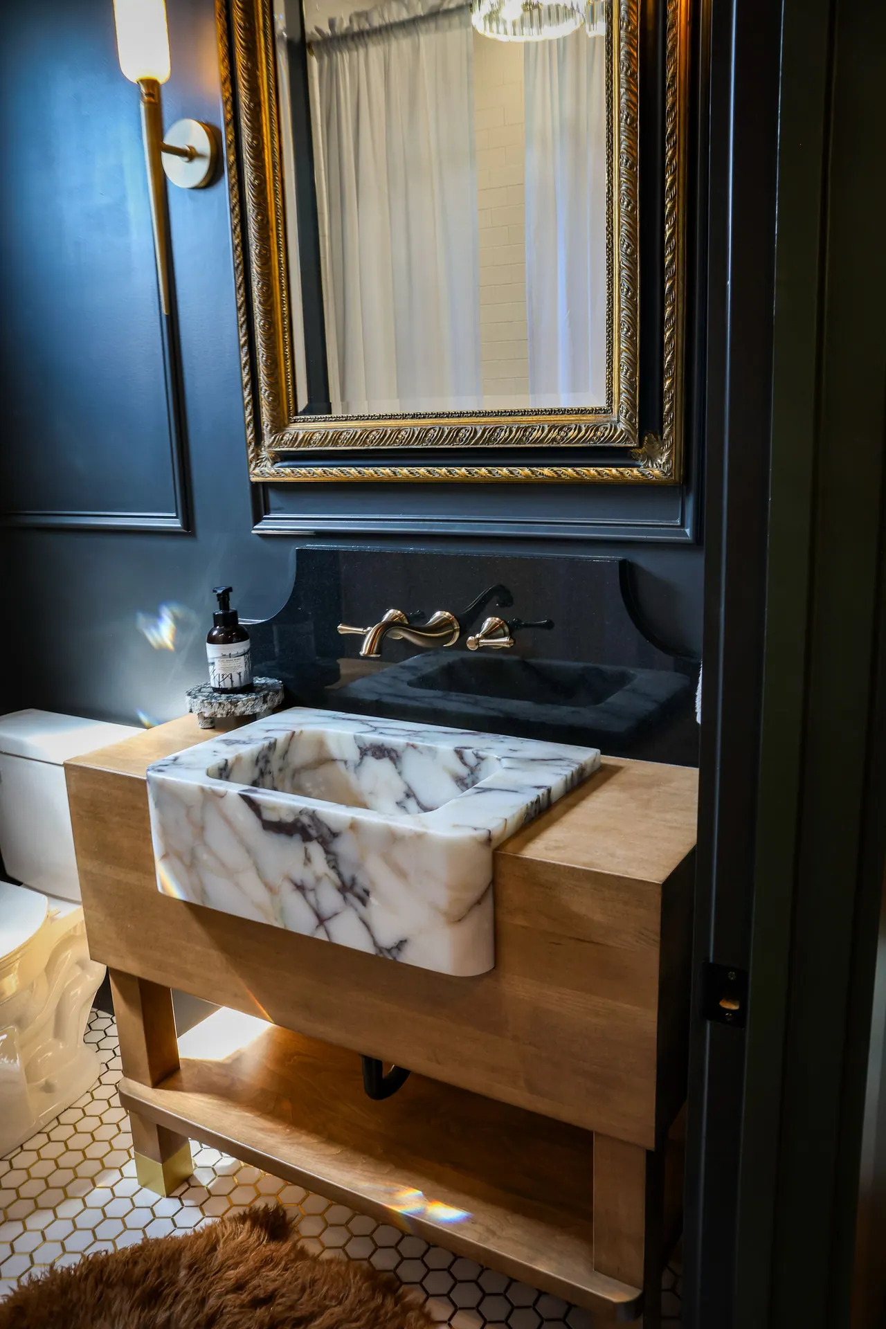 Wood vanity with marble vessel sink against a navy wall